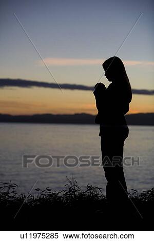A teenage girl prays at sunset by the ocean. View Large Photo Image Stock Photography - A teenage girl prays at sunset by the ocean.. Fotosearch