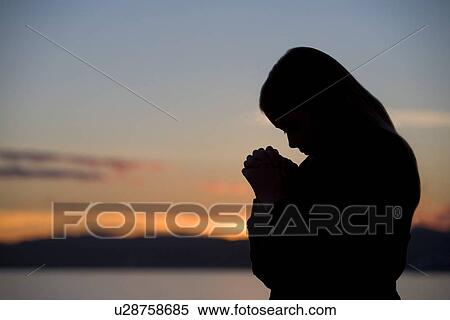 Stock Photography - A teenage girl prays at sunset. Fotosearch