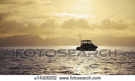 Stock Image - Boat on water at sunrise. Fotosearch