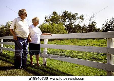 Stock Photograph - Couple looking over fence. Fotosearch