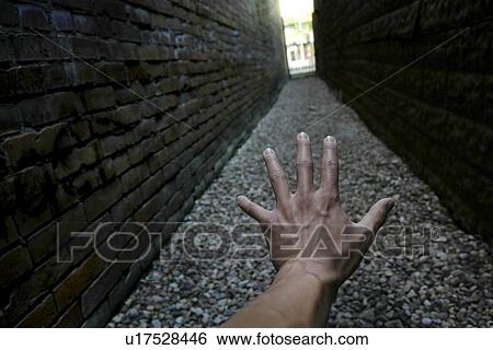 Hand reaching down narrow alley towards light View Large Photo Image Stock Photograph - Hand reaching down narrow alley towards light. Fotosearch