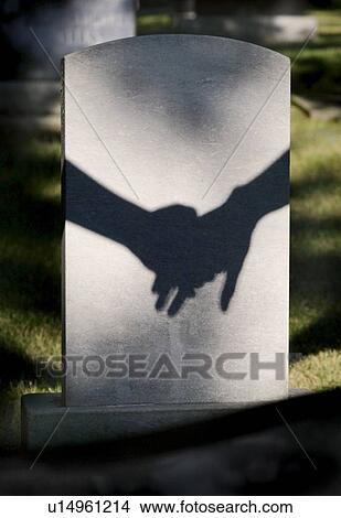 Picture - Shadow on tombstone of two clasped hands. Fotosearch