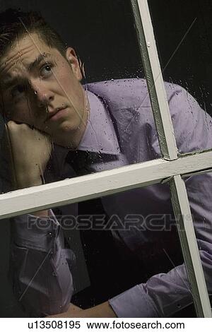 Stock Photography - Unhappy man looking out a window. Fotosearch