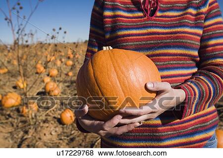 Woman holding a pumpkin View Large Photo Image Stock Photo - Woman holding a pumpkin. Fotosearch