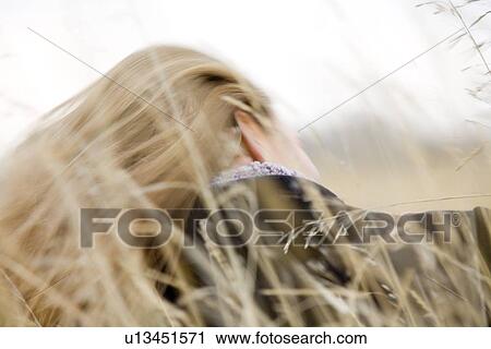 Stock Image - Woman sitting in wheat field. Fotosearch