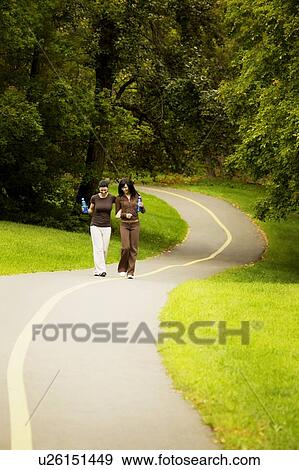 Young women walking arm in arm View Large Photo Image Stock Photo - Young women walking arm in arm. Fotosearch