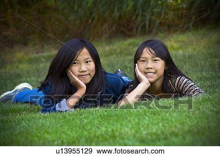 Stock Photo - Two sisters lying in the grass. Fotosearch