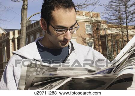 Stock Photo - Young man reading newspaper outside. Fotosearch