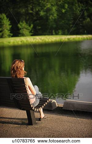 Woman sitting by a pond View Large Photo Image Stock Photography - Woman sitting by a pond. Fotosearch