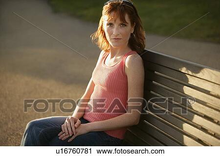 Woman sitting on a bench View Large Photo Image Stock Image - Woman sitting on a bench. Fotosearch