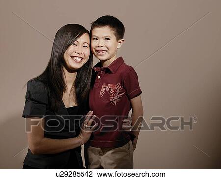 Stock Image - A mother with her arm around son's waist, smiling. Fotosearch