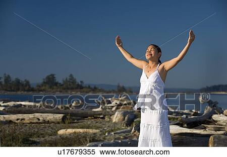 A young woman with arms raised on the beach View Large Photo Image Stock Photography - A young woman with arms raised on the beach. Fotosearch