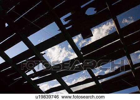 Stock Photograph - Blue sky though a tattered rooftop. Fotosearch