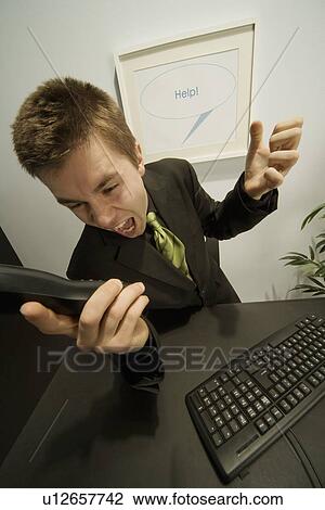 Stock Image - Businessman screaming into a phone. Fotosearch