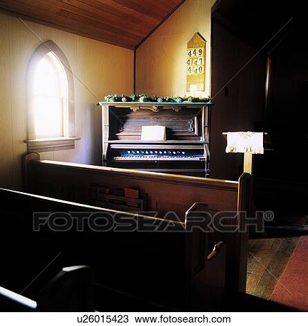 Stock Image - Chapel with wooden benches and organ in the corner. Fotosearch