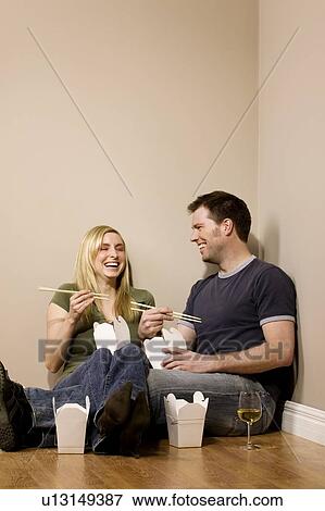Stock Photo - Couple eating on the floor. Fotosearch