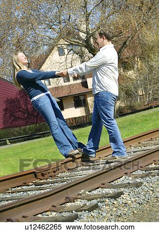 Couple holding hands on railroad track View Large Photo Image Stock Photography - Couple holding hands on railroad track. Fotosearch