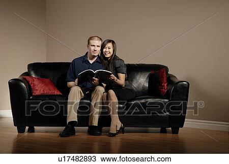 Stock Image - Couple reading together on the couch. Fotosearch