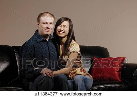 Couple sitting close on couch View Large Photo Image Stock Photo - Couple sitting close on couch. Fotosearch