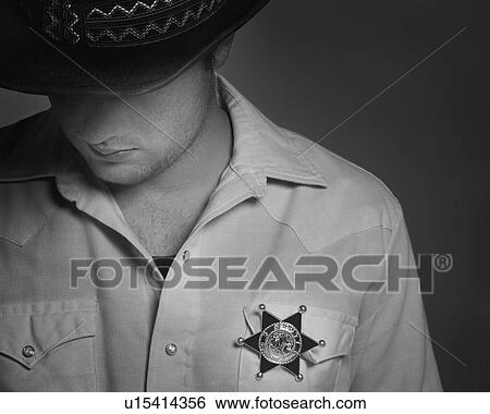 Cowboy looking down under hat with Sheriff's badge on shirt View Large Photo Image Stock Photograph - Cowboy looking down under hat with Sheriff's badge on shirt. Fotosearch