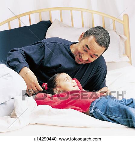 Stock Image - Father and little girl talking on a bed. Fotosearch