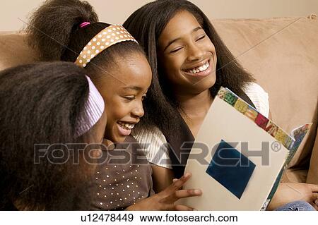 Stock Photo - Girls reading and laughing together. Fotosearch