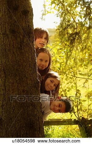 Stock Photo - Kids hiding behind tree trunk. Fotosearch
