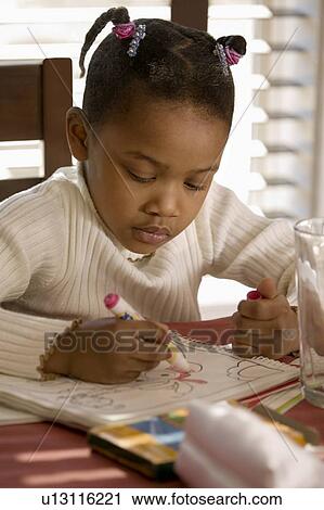 Stock Image - Little girl coloring a picture at the table. Fotosearch