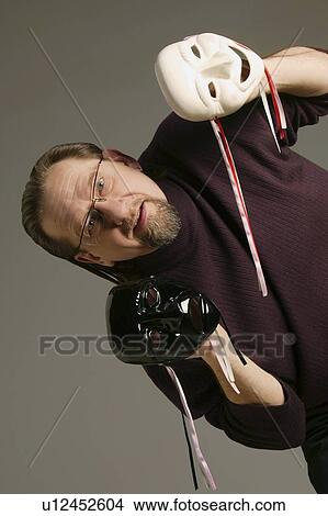 Picture - Man holding happy and sad face. Fotosearch