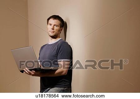 Man holding laptop View Large Photo Image Picture - Man holding laptop. Fotosearch