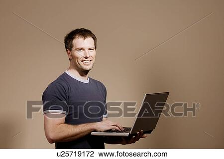 Stock Image - Man holding laptop. Fotosearch