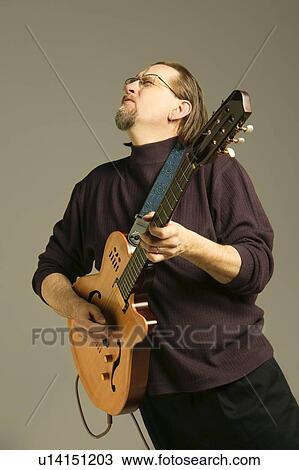 Middle aged man playing guitar looking upwards View Large Photo Image Stock Image - Middle aged man playing guitar looking upwards. Fotosearch