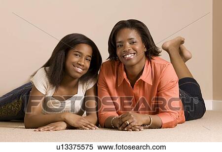 Stock Photography - Mother and daughter laying on the floor smiling and posing. Fotosearch