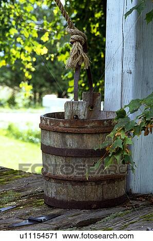 Stock Image - Old water bucket on top of well . Fotosearch