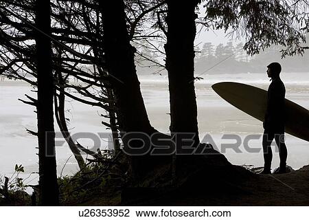 Stock Image - Silhouette of a surfer looking out to the water. Fotosearch