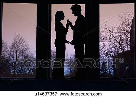 Stock Photo - Silhouette of couple facing each other and touching hands. Fotosearch
