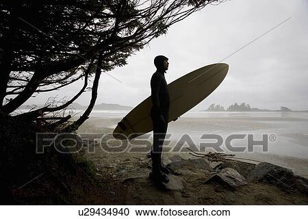 Stock Image - Surfer observing water from the beach. Fotosearch