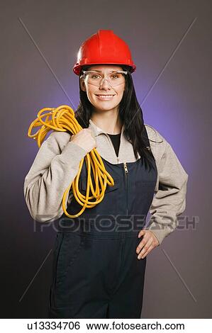 Tradeswoman in coveralls, holding an extension cord View Large Photo Image Stock Photograph - Tradeswoman in coveralls, holding an extension cord. Fotosearch