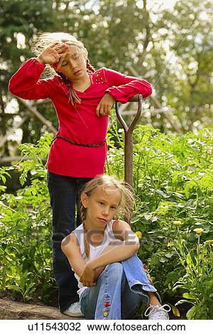 Stock Image - Two girls resting from garden work. Fotosearch