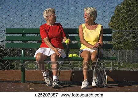 Two senior women sitting with tennis rackets View Large Photo Image Stock Photo - Two senior women sitting with tennis rackets. Fotosearch
