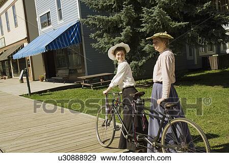Stock Photo - Two women with a vintage bicycle built for two. Fotosearch
