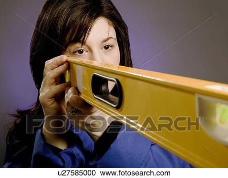 Stock Image - Woman holding a spirit level. Fotosearch