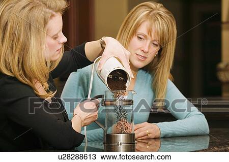 Stock Image - Woman making coffee in a french press. Fotosearch