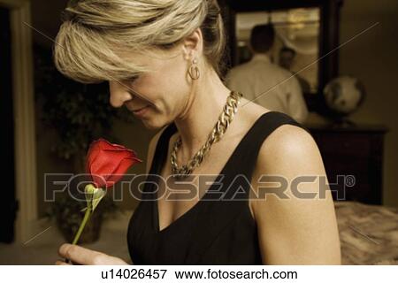 Stock Photo - Woman smelling a red rose. Fotosearch