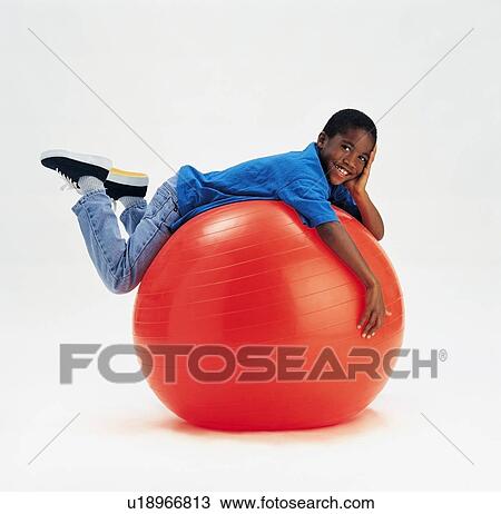 Stock Image - Young boy laying on large red ball. Fotosearch