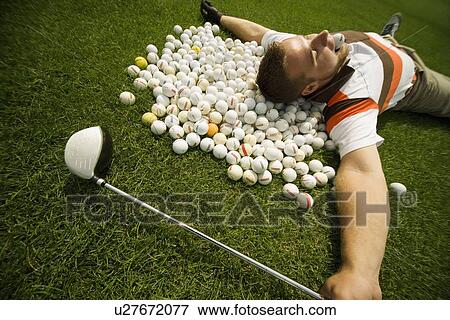 Stock Photo - A man lying on golf balls. Fotosearch