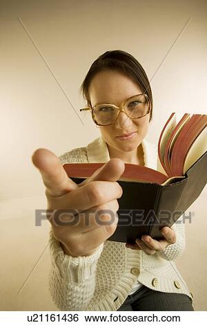 A woman holding book and pointing to the camera View Large Photo Image Stock Photograph - A woman holding book and pointing to the camera. Fotosearch