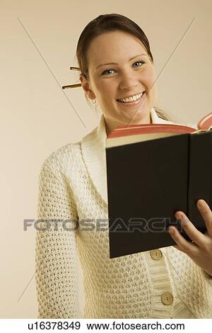 Stock Photo - A woman smiling and reading book. Fotosearch