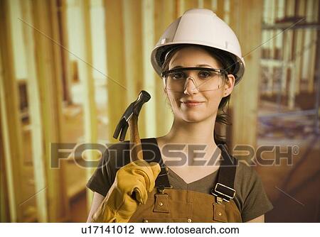 A woman wearing construction hat and holding a hammer View Large Photo Image Stock Image - A woman wearing construction hat and holding a hammer. Fotosearch