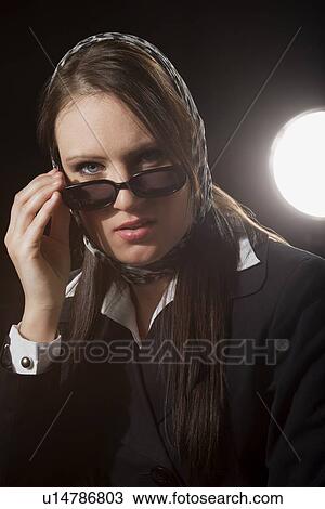A young woman peering over sunglasses View Large Photo Image Stock Image - A young woman peering over sunglasses. Fotosearch